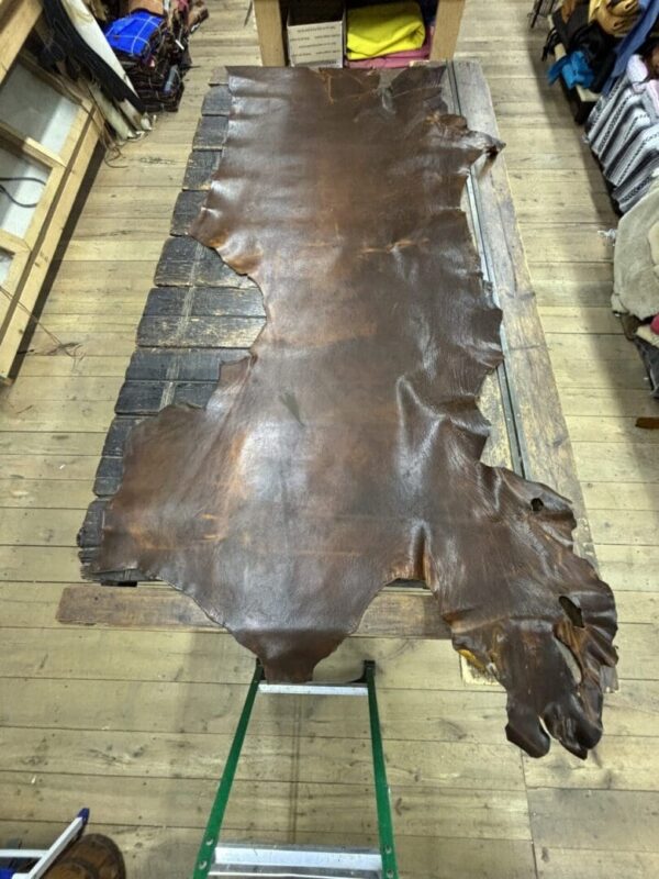 Leather hide laid out on wooden table.