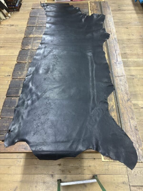 Black leather hide on wooden table.