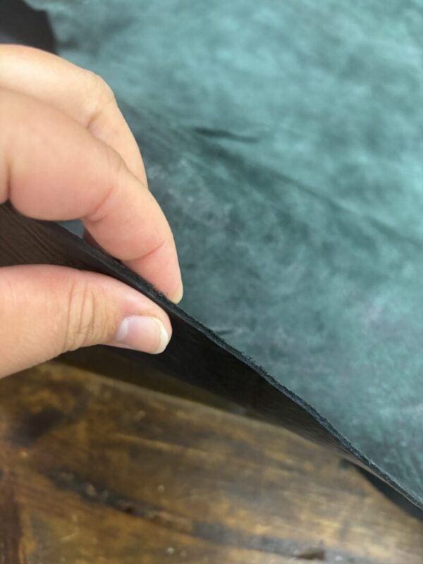 Hand holding green leather sheet.