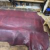 Burgundy leather hide on a wooden table.