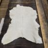 White cowhide rug on wooden floor.