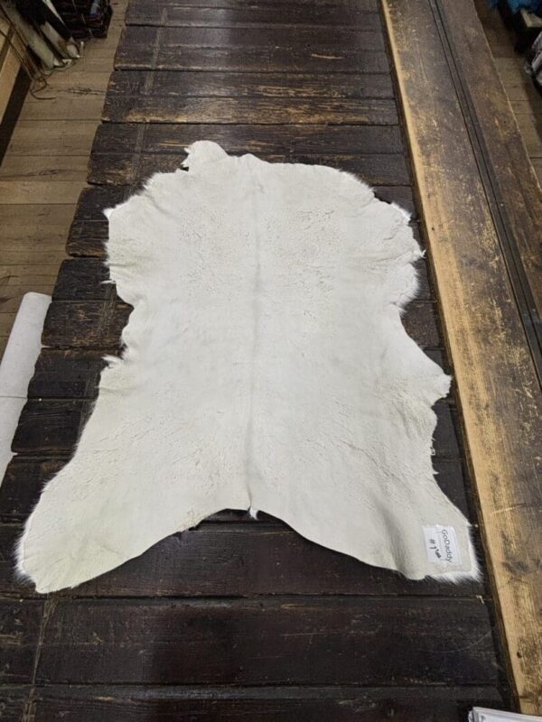 White cowhide rug on wooden floor.