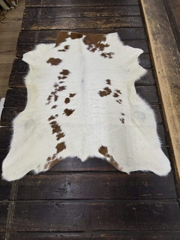 White cowhide rug with brown spots.