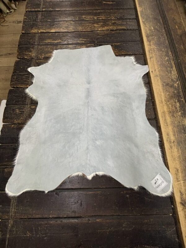 Light gray cowhide rug on wood floor.