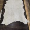 White goat skin fur rug on wood floor.