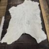 White cowhide rug on wooden floor.