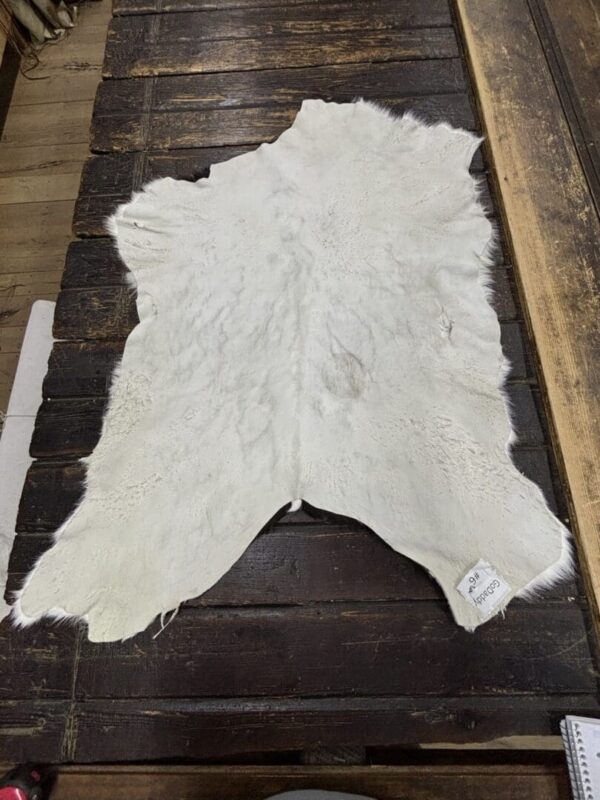 White cowhide rug on wooden floor.