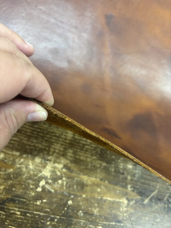 Hand holding brown leather sheet.