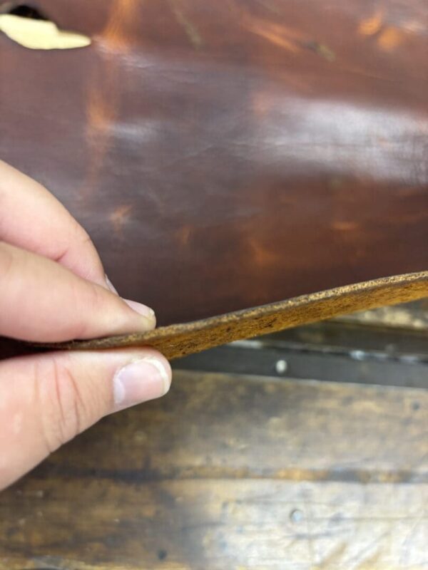 Hand holding thick brown leather.