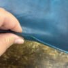 Hand holding a piece of teal leather.