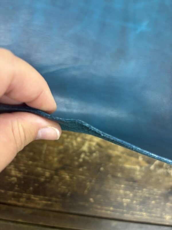 Hand holding a piece of teal leather.