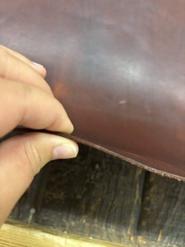 Hand holding a piece of brown leather.