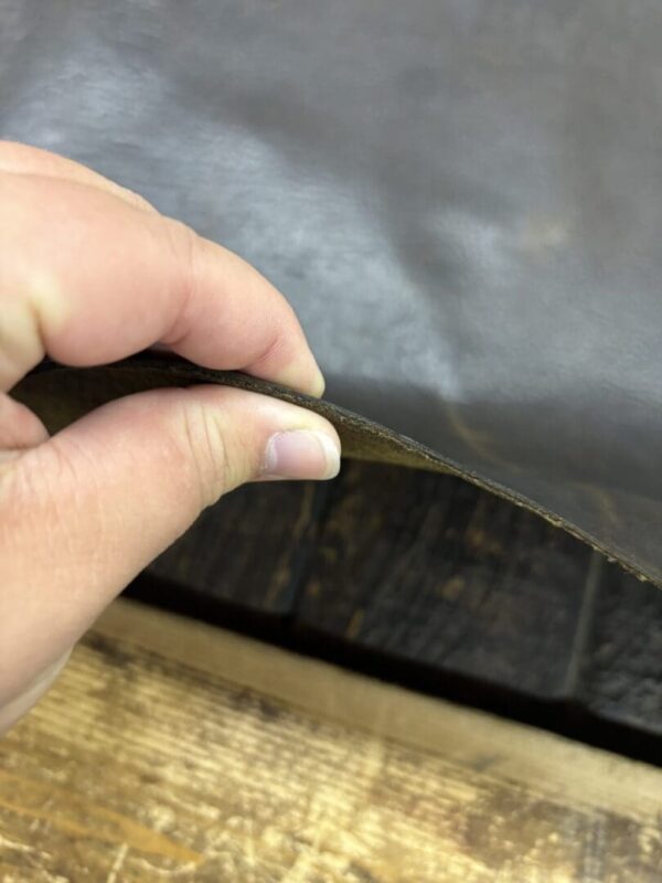 Hand holding a piece of leather.