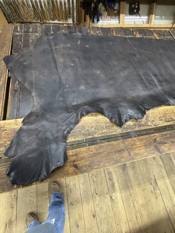 Large black leather hide on wooden surface.