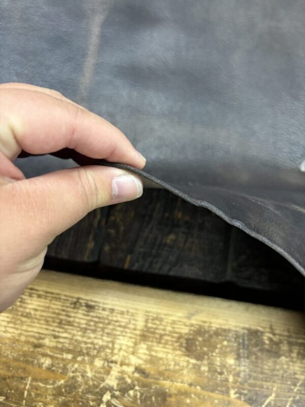 Hand holding dark brown leather sheet.