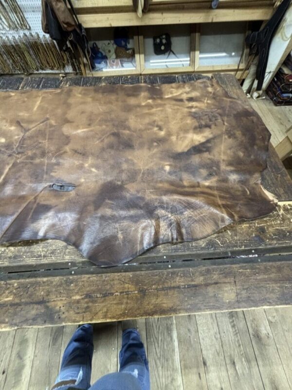 Large piece of brown leather on wood table.