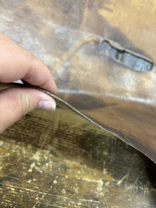 Closeup of brown leather with a hole.