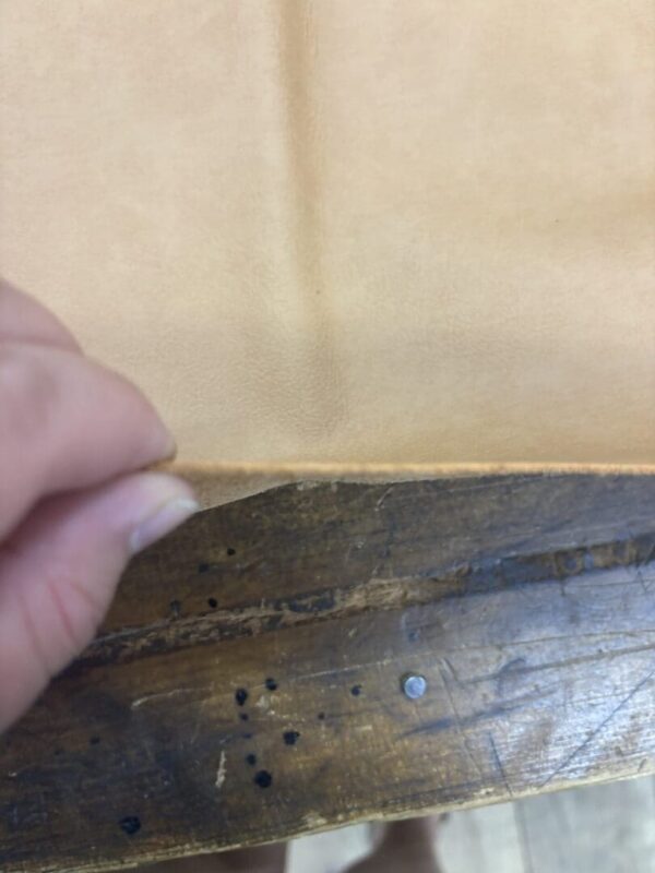 Hand holding light tan leather.