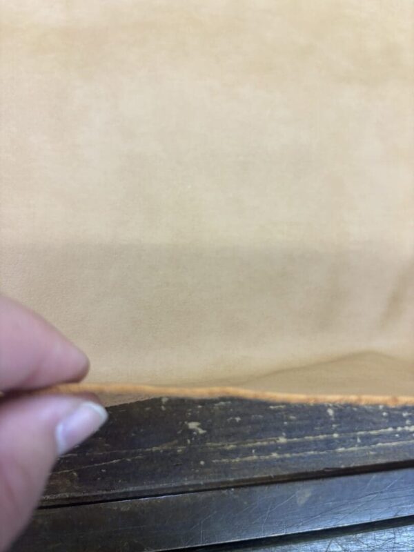 Hand holding tan leather edge.