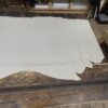Off-white leather hide on wooden table.