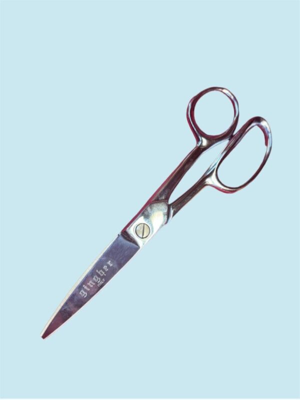 Silver Gingher scissors on blue background.