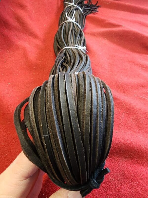 Bundle of black leather strips on red fabric.