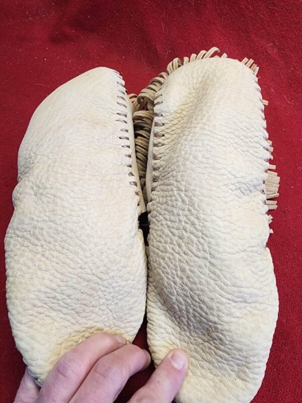 Handmade leather moccasins on red background.