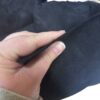 Hand holding black suede fabric piece.