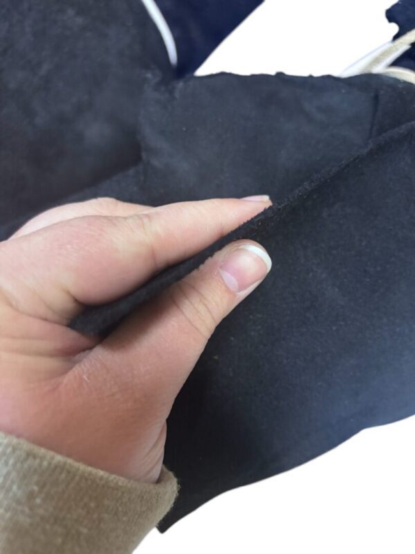 Hand holding black suede fabric piece.